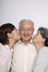 Senior man getting kisses from senior woman and woman