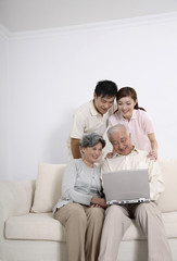 Fototapeta na wymiar Senior man using laptop while senior woman, woman and man watches him