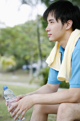 Man with towel around his neck, holding water bottle