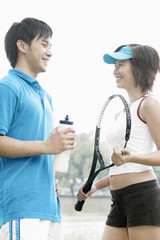 Woman with tennis racquet talking to man
