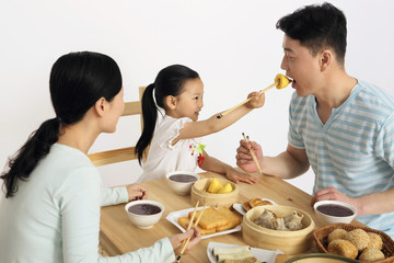 Girl feeding man dim sum using chopsticks