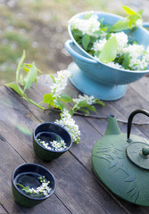 beautiful garden fresh flower tea kettle on wooden table outdoor setting, herbal floral background