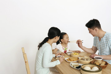 Man feeding girl dim sum using chopsticks