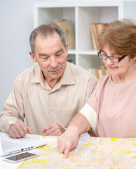 Senior couple look at map and plan holiday