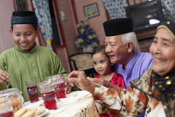 Senior man and woman enjoying cookies with their grandchildren