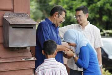 Fototapeta premium Woman greeting senior man, man and boy watching
