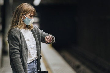 Woman looking at her watch while waiting for the train during the coronavirus pandemic