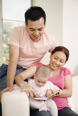 Obraz premium Man and woman reading book for baby