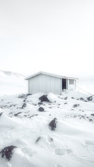White abandoned wooden cabin in the snowy countryside of Greenland