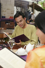 Man and woman reading menu at restaurant