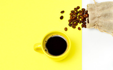 yellow cup of coffee on a double yellow-white background with a bag with natural coffee beans. The concept of morning coffee, breakfast.
