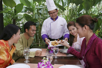 Chef serving food, man and women looking at the food happily