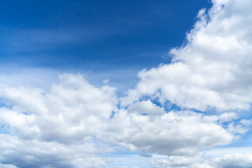 Naklejka na ściany i meble Overcast white clouds on the side of blue sky. Fluffy clouds background