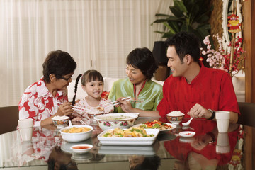 Couple and senior woman paying attention to girl while having lunch together