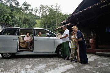 Senior man and woman standing at house compound, greeting man and boys