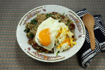 Traditional fried cooked rice with sausage, basil and chilly seasoning with fish sauce and pepper. Topping with fried chicken egg. Special street food menu in Asia. Famous comfortable fast food