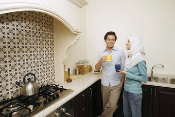 Man and woman enjoying drink while chatting in the kitchen