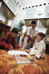 Boy and girl colouring their books, man and woman watching