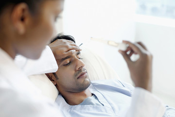 Obraz na płótnie Canvas Doctor checking on patient's temperature