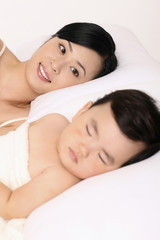 Obraz na płótnie Canvas Woman looking at baby girl asleep beside her