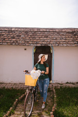 A beautiful young caucasian woman with a straw hat next to a bicycle with flowers in a basket