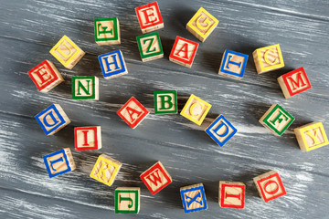 Multicolored wooden cubes with letters on gray background. Set for studying alphabet. Education,...