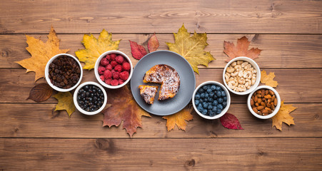 Seasonal autumn background. Frame of maple leaves and a cake over wooden background.