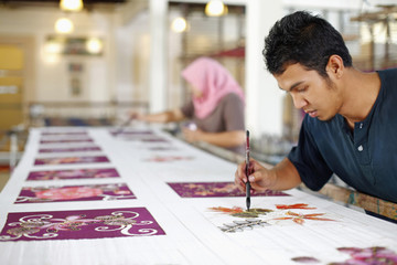 Man and woman painting batik fabric