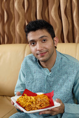 Man holding a plate of Indian snacks