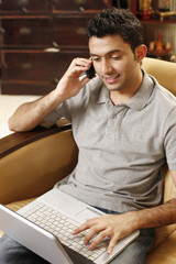Man talking on the phone while using laptop