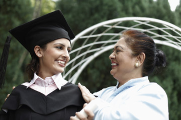 Fototapeta premium Senior woman and woman in graduation gown smiling at each other