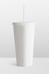 White disposable cup with a plastic lid and a straw