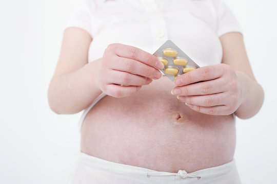 Pregnant Woman Taking Supplement From Blister Pack