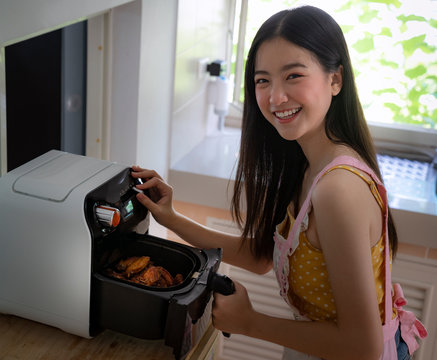 Asian girl cooking a fried chicken by Air Fryer machine