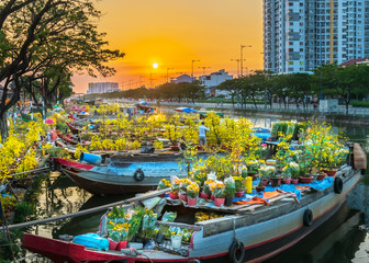 Fototapeta na wymiar Flower boats full of flowers parked along canal wharf in sunset, a place for bustling flower market trade lunar new year in Ho Chi Minh City, Vietnam