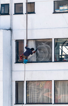 Obrero limpia ventanas en exterior de edificio con pocas medidas de seguridad, Ciudad de M&eacute;xico