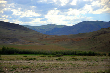 A fertile pasture stretching in a picturesque valley between high mountains.