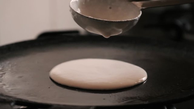 Closeup slow motion view of  steaming hot 'Dosa' on a cast iron pan. Dosa is the Indian version of pancake made with rice flour dough
