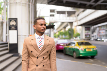 Young handsome African businessman waiting for taxi in the city