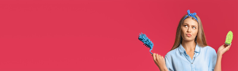 Portrait of beautiful chambermaid holding brushes on color background with space for text