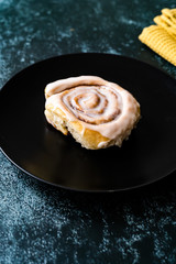 Cinnaom Roll / Cinnamon Bun with Cream in Dark Black Plate Ready to Eat