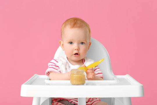 Little baby eating food against color background