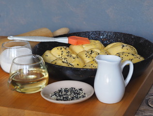 Homemade cooking. Raw rolls of wheat dough on a kitchen board with ingredients.