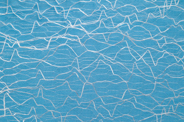 Guipure lying on a colored cloth, photographed close-up. Background for the texture of outerwear and fashion.