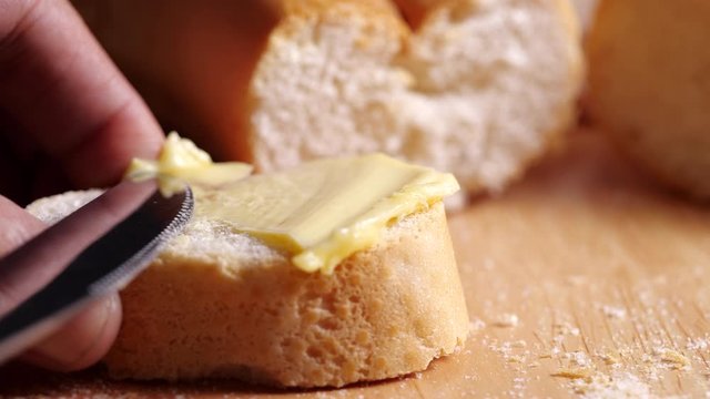 Spreading soft butter on homemade bread in 4k slow motion. Knife smearing soft butter on slice of bread