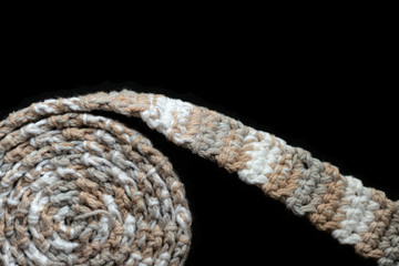 Crochet tape melange yarn brown and beige color on a black background close-up. Top view. Hand-made concept