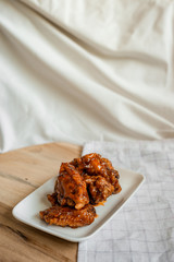 fried chicken wings with spicy sauce on cutting board