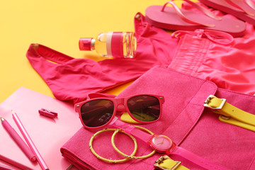 Female accessories and clothes with stationery on color background