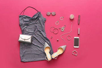 Female accessories and clothes with mobile phone on color background