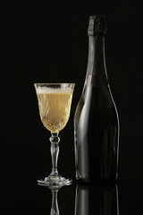 Glass and bottle of champagne on dark background